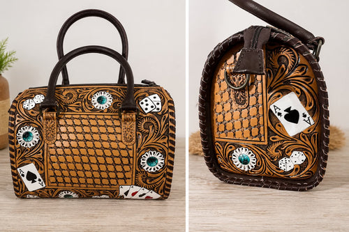 A tooled brown leather handbag with dark brown handles, featuring a snakeskin pattern, tooled floral scrollwork, faux turquoise accents, and playing card motifs including an Ace of Spades and dice. Shown in a split view of the front and side profile on a light wood surface.